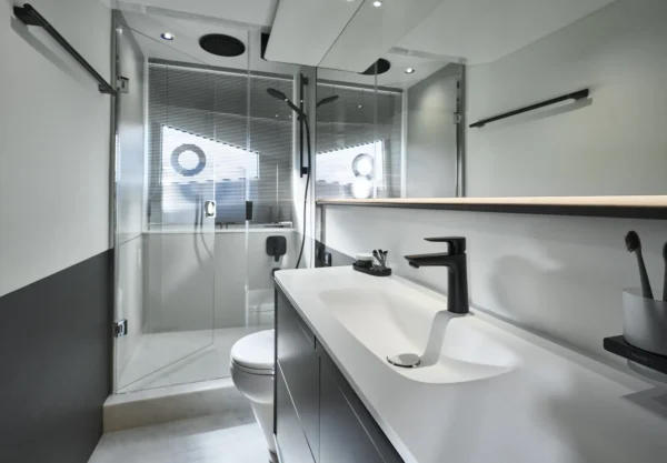 Modernes Badezimmer auf der Princess S65, ausgestattet mit einer eleganten Dusche, gläsernen Trennwänden und minimalistischen Armaturen in Schwarz.