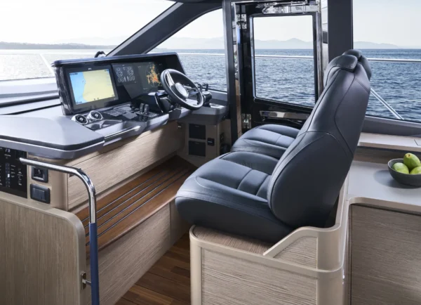 Stilvoller Steuerstand der Princess S65 mit zwei luxuriösen schwarzen Kapitänssitzen, modernem Navigationssystem und einem großzügigen Panoramafenster für optimalen Ausblick. Der Raum kombiniert Funktionalität mit einem gehobenen, eleganten Ambiente.