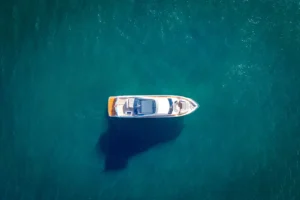 Luftaufnahme einer eleganten, modernen Princess Yacht Y85, die auf tiefblauem Wasser treibt, mit einem deutlichen Schatten, der unter dem Schiff sichtbar ist